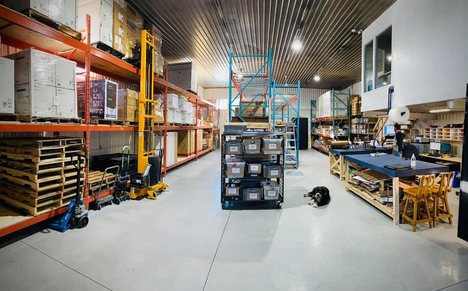 Le premier local déjà rempli : racks chargés, tables d'emballage, Moby, le chien, couché dans l'allée